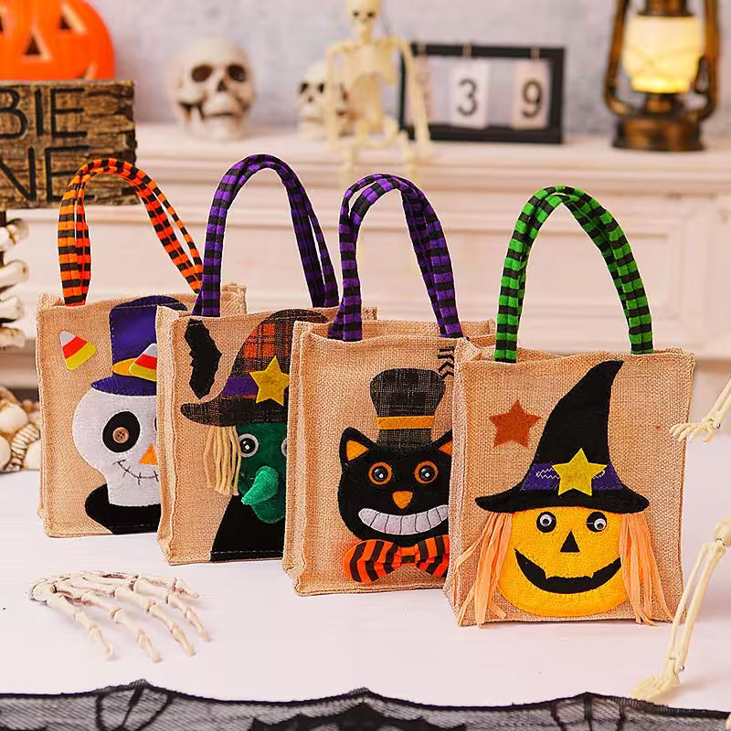 Four Halloween-themed jute bags with decorative handles on a table.