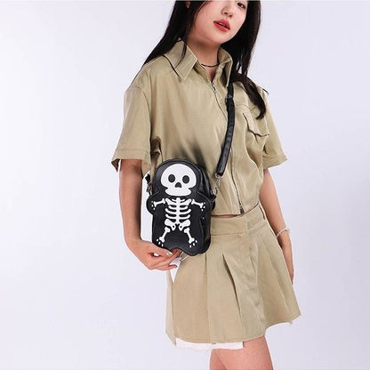 Person wearing a beige outfit with a black bag featuring a skull and bone design on a white background