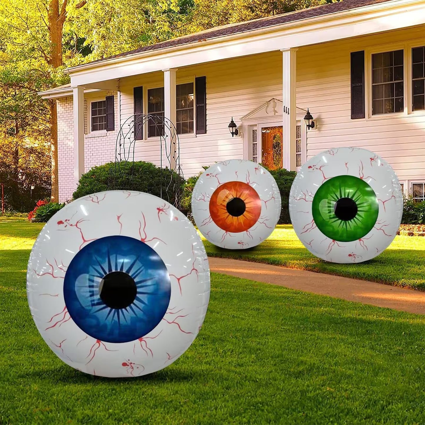 Three large inflatable eyeball decorations in front of a house.