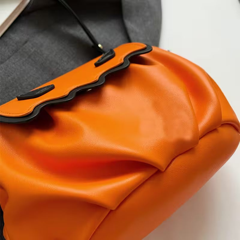 Close-up of an orange drawstring bag with black accents on a blurred background