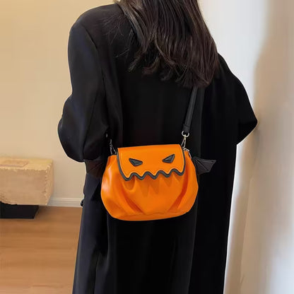 Person wearing a black outfit with an orange pumpkin-shaped bag featuring a face design.
