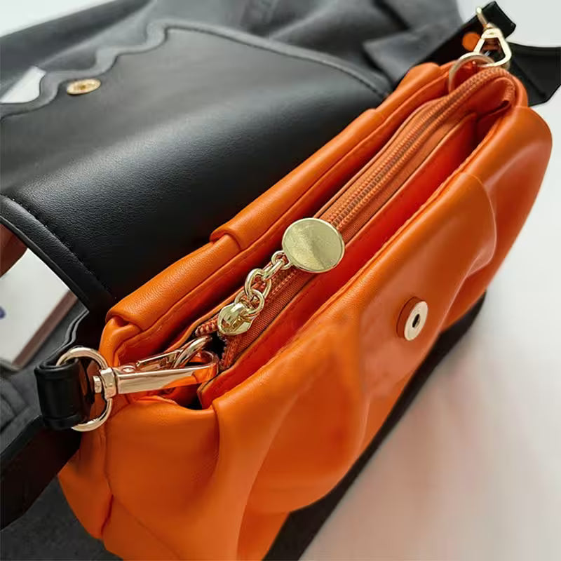 Close-up of an orange handbag with gold accents on a neutral background