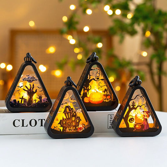 Four triangular Halloween-themed night lights on a surface with a blurred background of lights and plants.