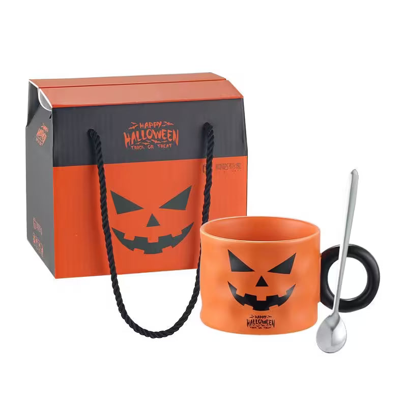 Halloween-themed mug with black handle and pumpkin face design, next to a matching gift bag on a white background.