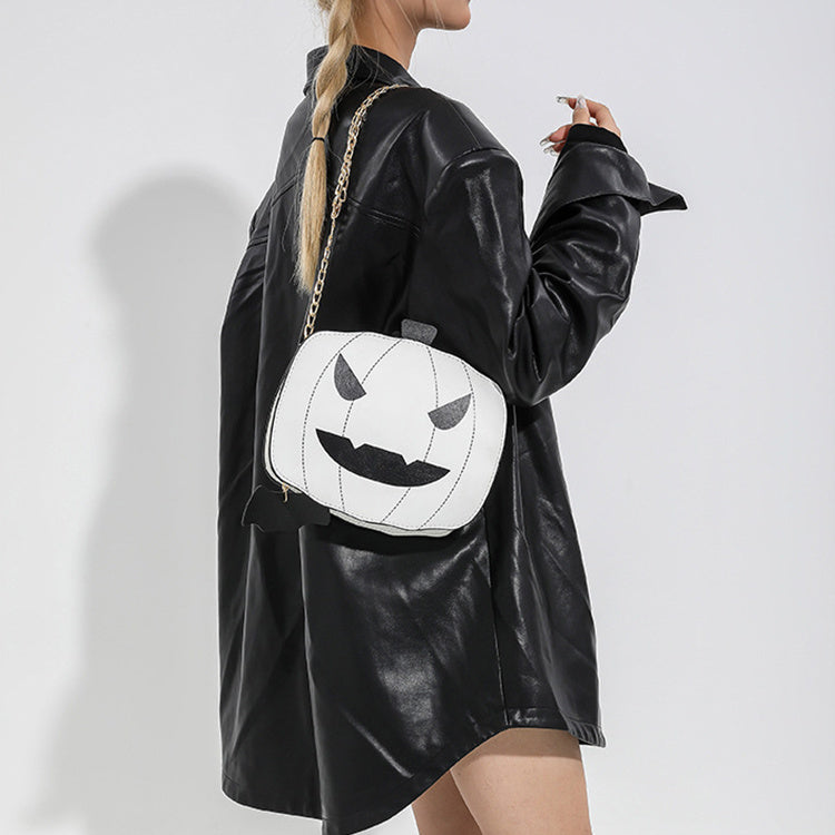 Person wearing a black leather jacket with a white pumpkin face bag on a plain background
