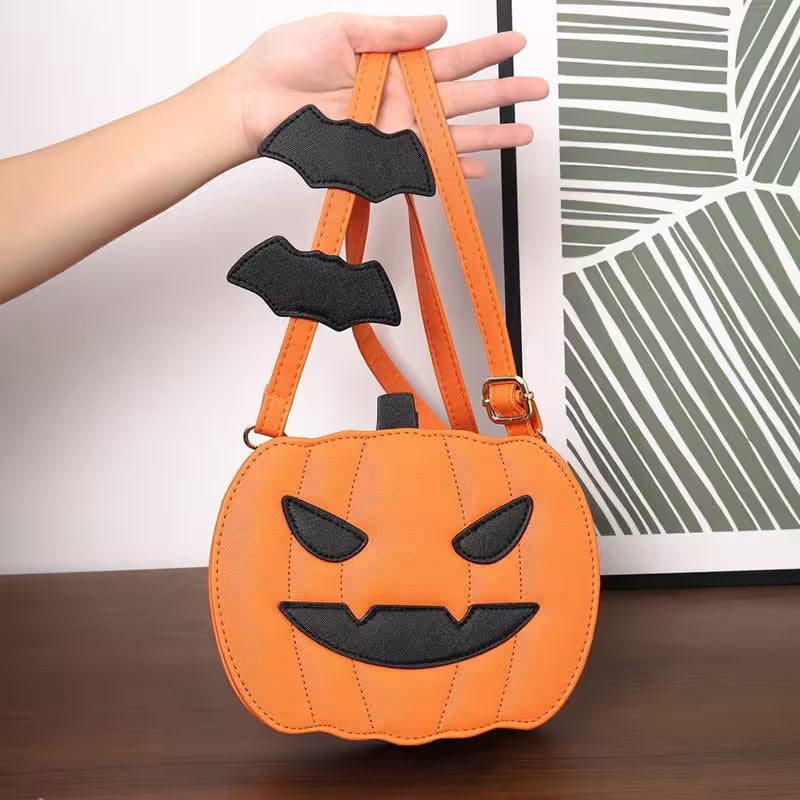 Orange pumpkin-shaped bag with black face details held by a hand on a wooden surface.