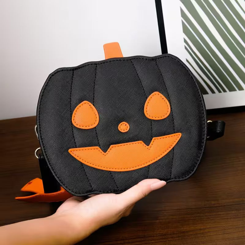 Black pumpkin-shaped bag with orange accents held by a hand on a wooden surface.