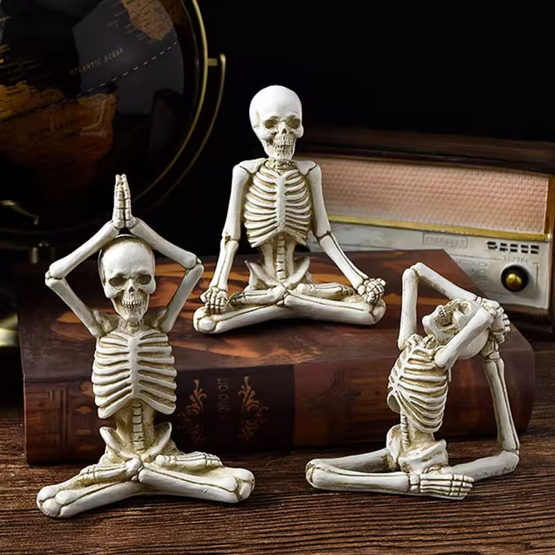 Three skeleton figurines in yoga poses on a wooden surface with a vintage radio in the background.