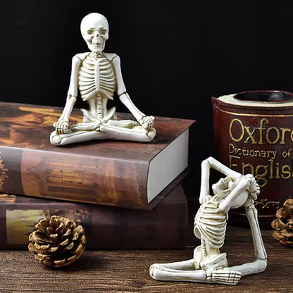 Two skeleton figurines in yoga poses on books with a 'Dictionary of English' book in the background.