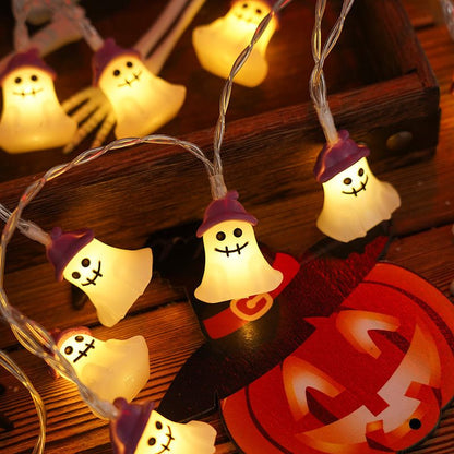 Halloween-themed string lights with ghost characters on a wooden surface with a pumpkin.
