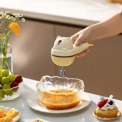 Person using a cartoon-themed whisk to mix ingredients in a bowl on a table with fruits and pastries.