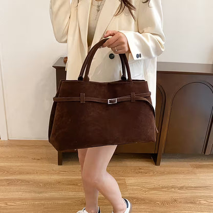Person holding a brown leather handbag indoors