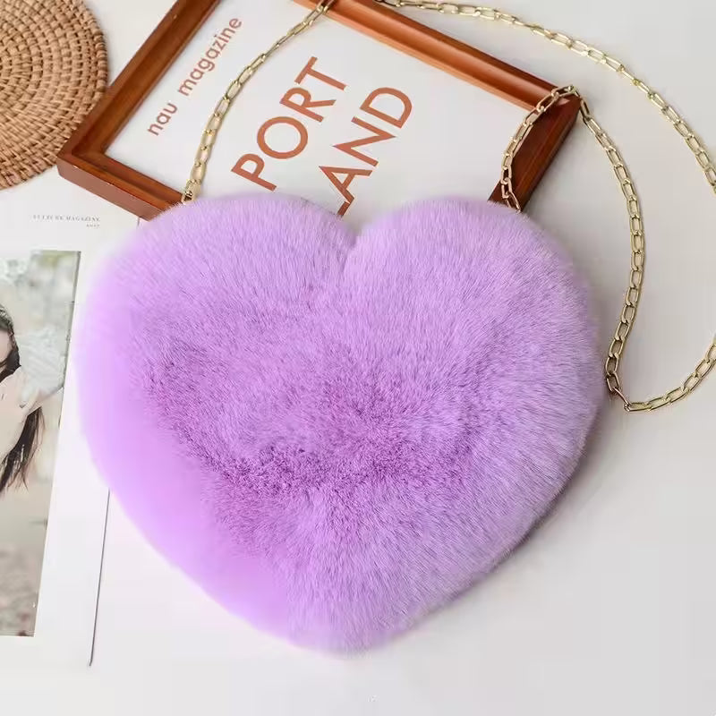 Heart-shaped purple fur bag with a gold chain on a magazine background