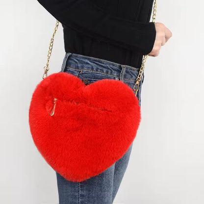Red fluffy heart-shaped handbag held by a person against a white background