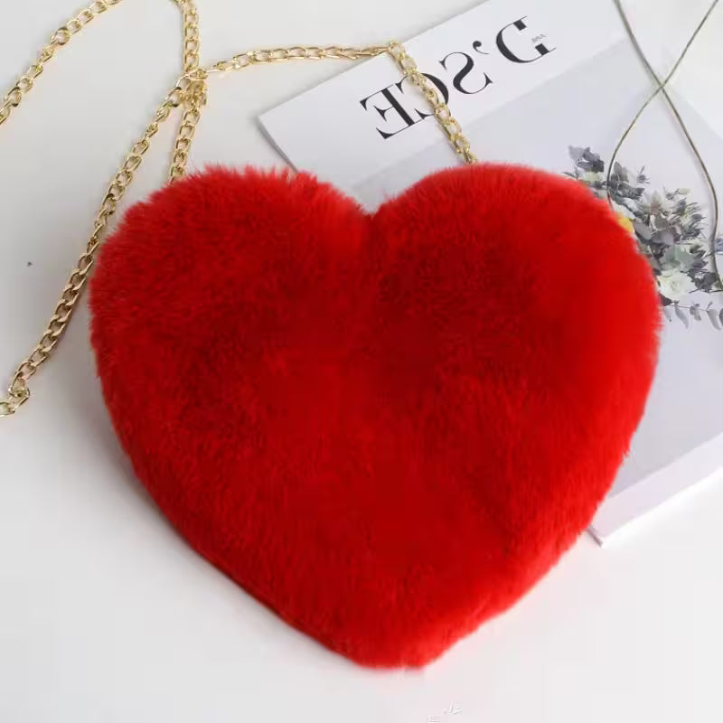 Red heart-shaped bag with a gold chain on a white surface