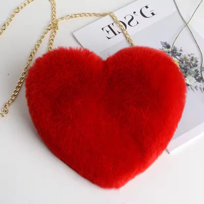 Red heart-shaped bag with a gold chain on a white surface