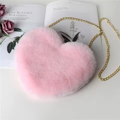Pink fluffy bag with a gold chain on an open book with floral designs.
