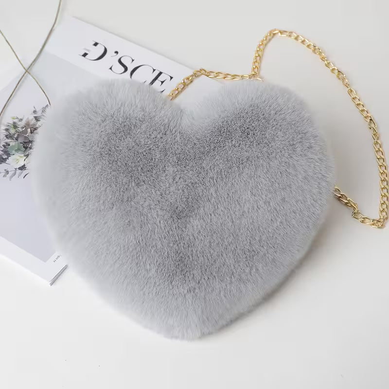 Heart-shaped gray fur bag with a gold chain on a white background