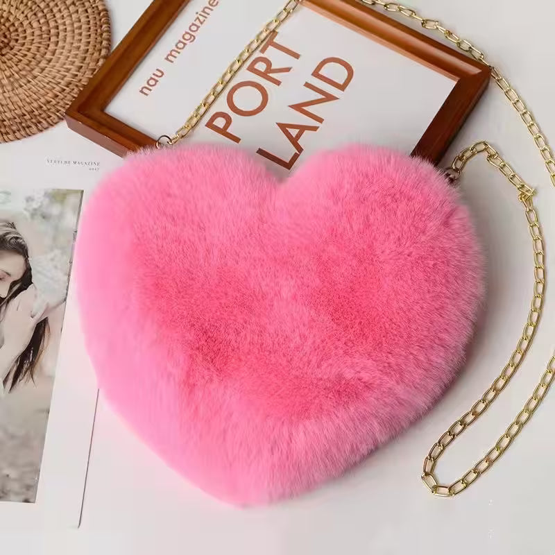 Pink heart-shaped fur bag with a gold chain on a magazine background
