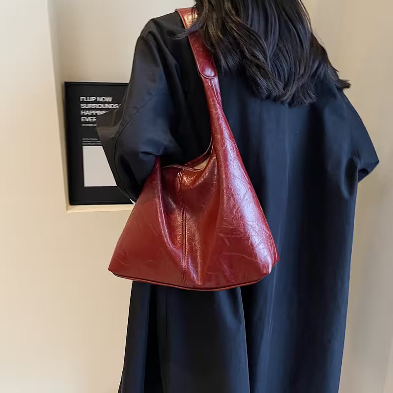 Person wearing a dark coat with a red leather handbag on a plain background