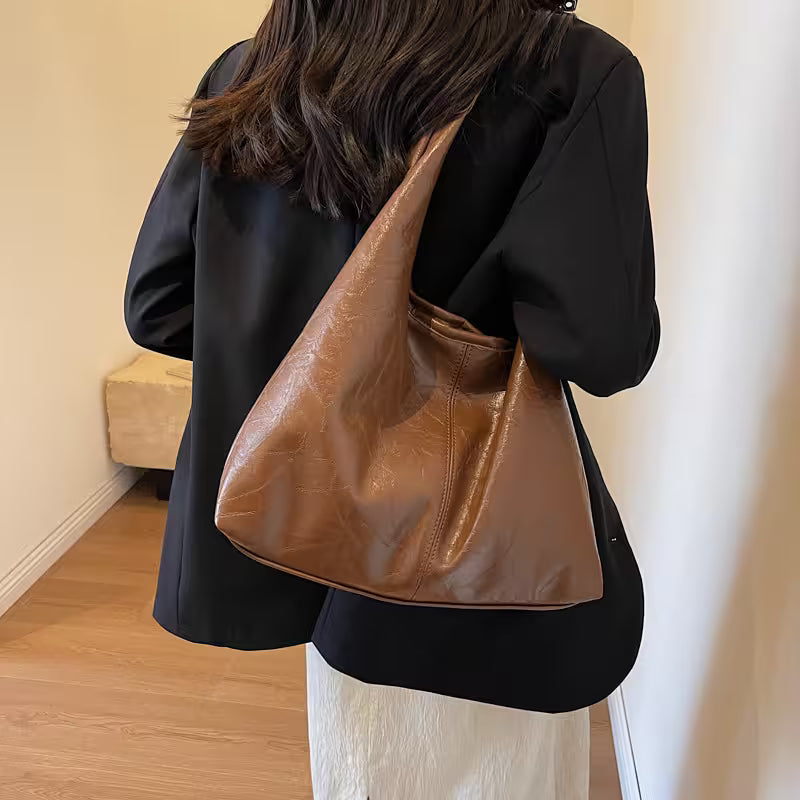 Person wearing a black outfit with a brown leather handbag.