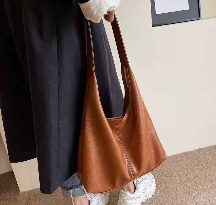 Person holding a brown leather handbag indoors