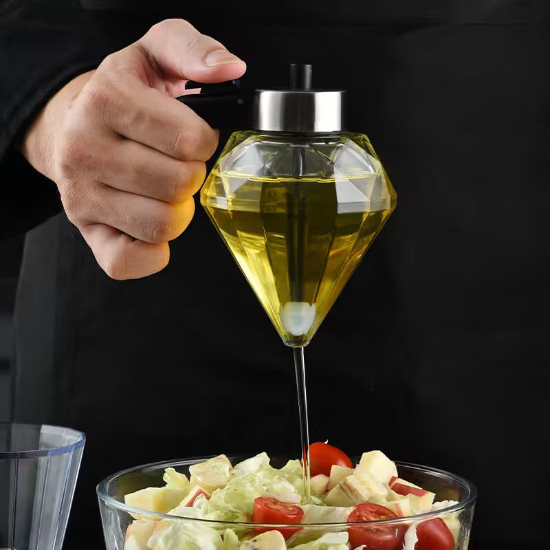 Person using a diamond-shaped olive oil dispenser to drizzle oil over a salad.