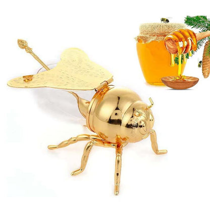 Gold bee-shaped container with a honeycomb and jar of honey on a white background