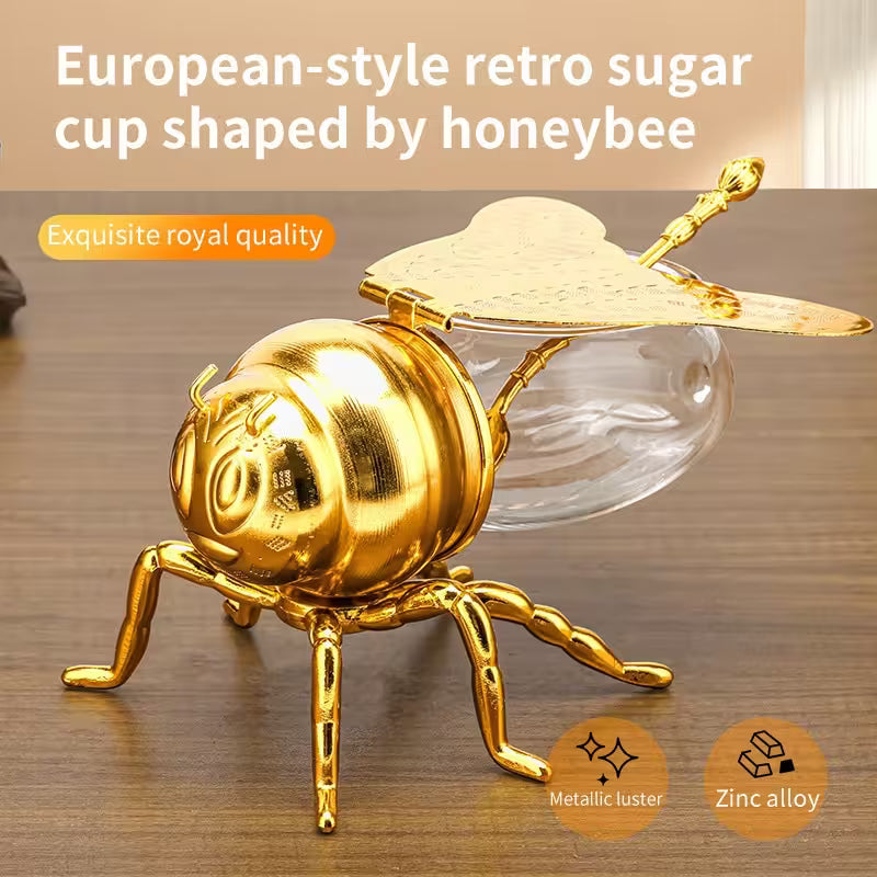Gold honeybee-shaped sugar cup with clear glass body on a wooden surface
