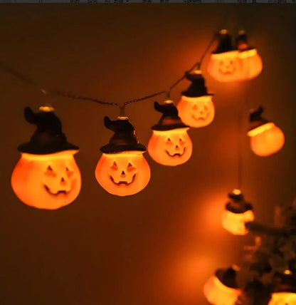 String of Halloween-themed lights shaped like jack-o'-lanterns with witch hats on a dark background.