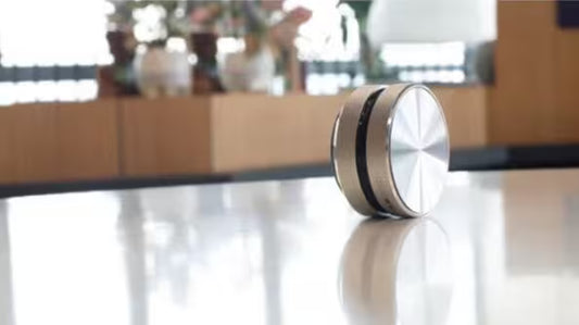 Silver cylindrical object on a reflective surface with a blurred indoor background