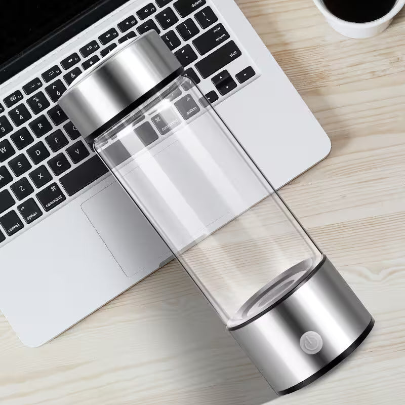 Clear and silver water bottle on a desk with a laptop and cup of coffee