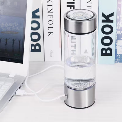 Silver water bottle with USB cable on a surface with books in the background