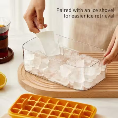 Clear ice container with a yellow ice cube tray on a table.