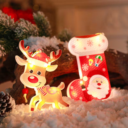 Decorative Christmas reindeer and stocking with lights on a snowy surface.