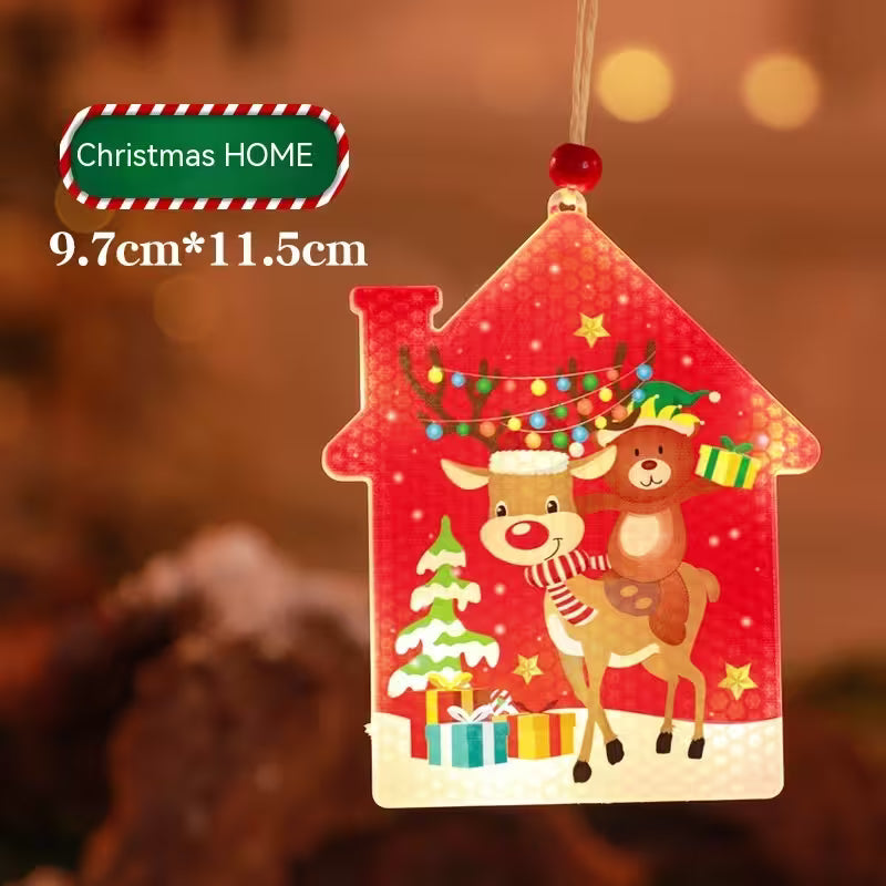 Red house-shaped Christmas ornament with reindeer, tree, and presents on a blurred background.