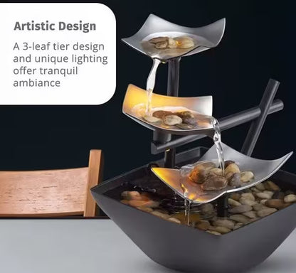 Decorative water fountain with three tiered bowls and pebbles on a dark background