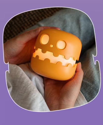 Hand holding a glowing orange pumpkin-shaped light with a purple border