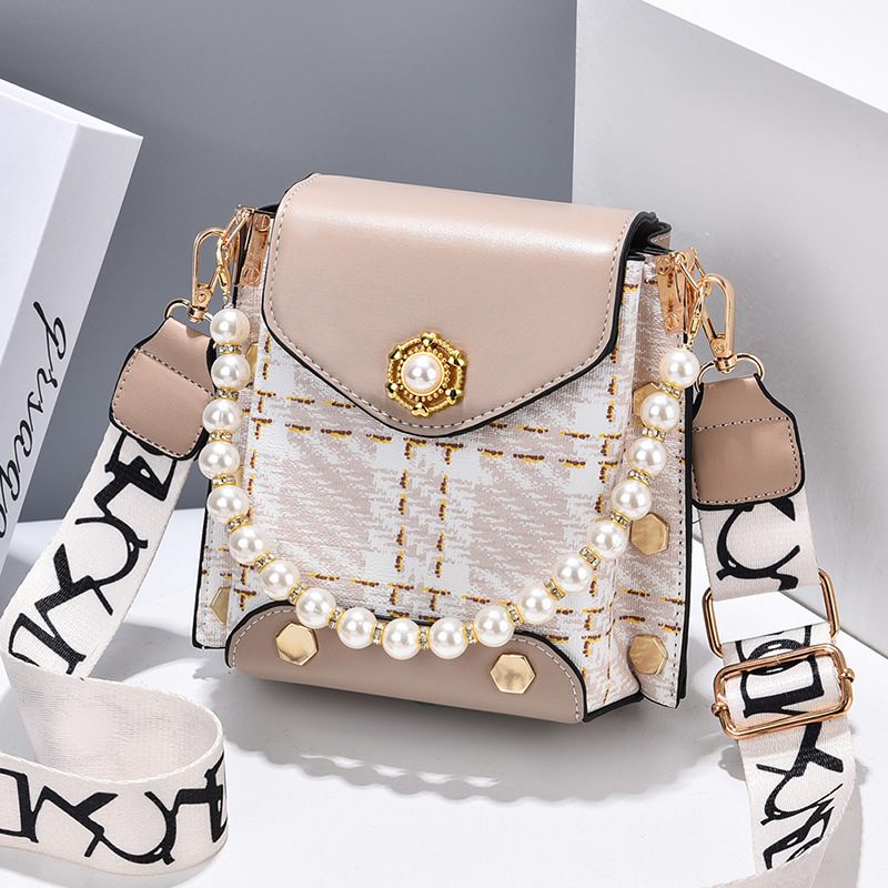 Beige handbag with pearl embellishments on a light gray background