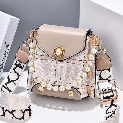 Beige handbag with pearl embellishments on a light gray background