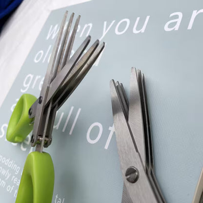 Green-handled scissors and metal tongs on a magazine with text.
