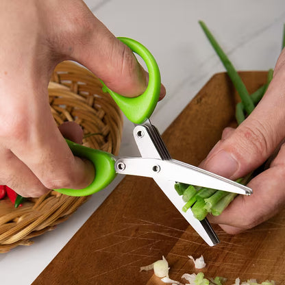 Person using green-handled scissors to trim green onions on a wooden cutting board.