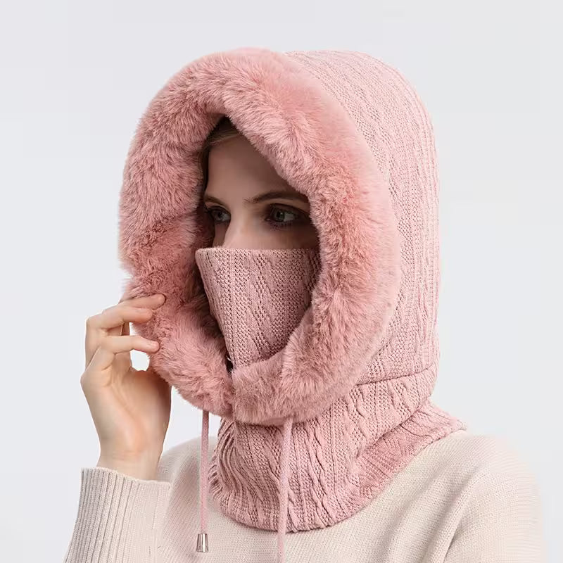 Person wearing a pink knitted hood and mask on a light gray background