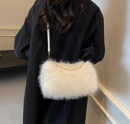 Person wearing a black coat holding a fluffy white handbag with a gold chain strap.