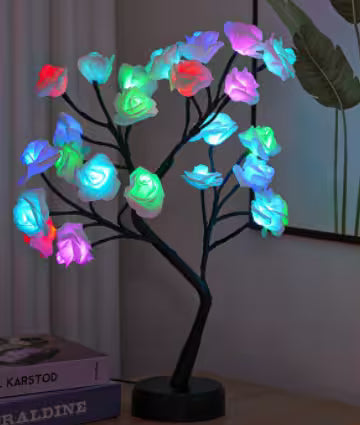 Colorful LED tree lamp on a table with books in the background