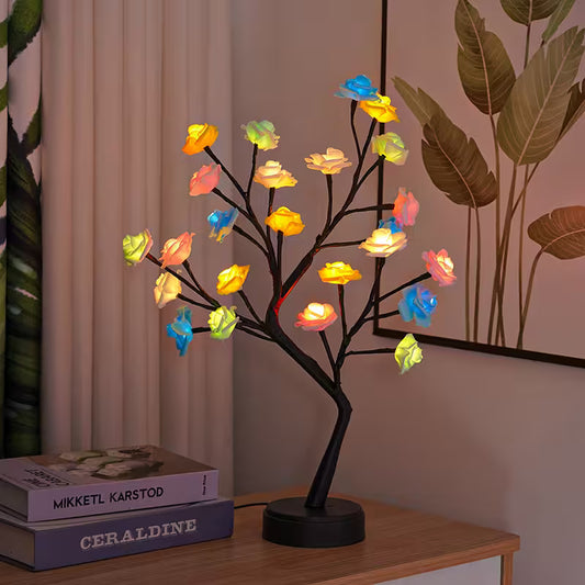 Decorative LED tree with colorful lights on a wooden surface next to books.