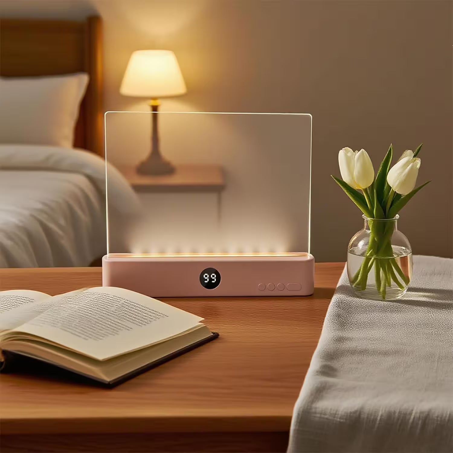 Pink lamp on a bedside table with a book, vase of tulips, and lamp in the background.