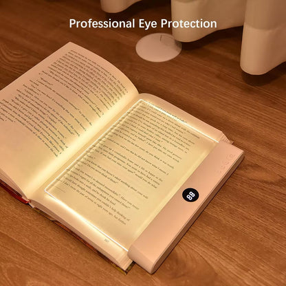 Open book with a light pad on a wooden surface, emphasizing eye protection.