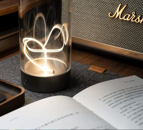 Glass lamp with decorative light inside on a table next to an open book and a Mars product box.