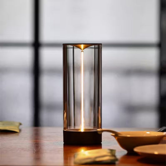 Cylindrical table lamp with a warm glow on a wooden surface.